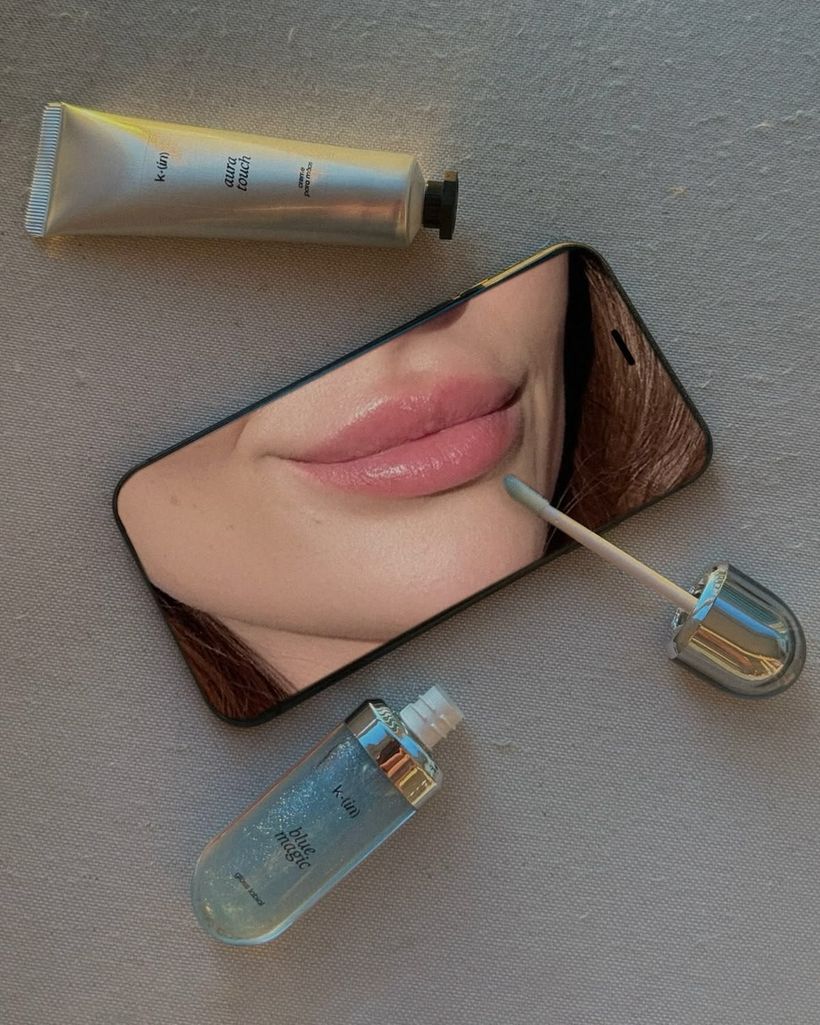 Productos de skincare y labial sobre una mesa junto a un teléfono